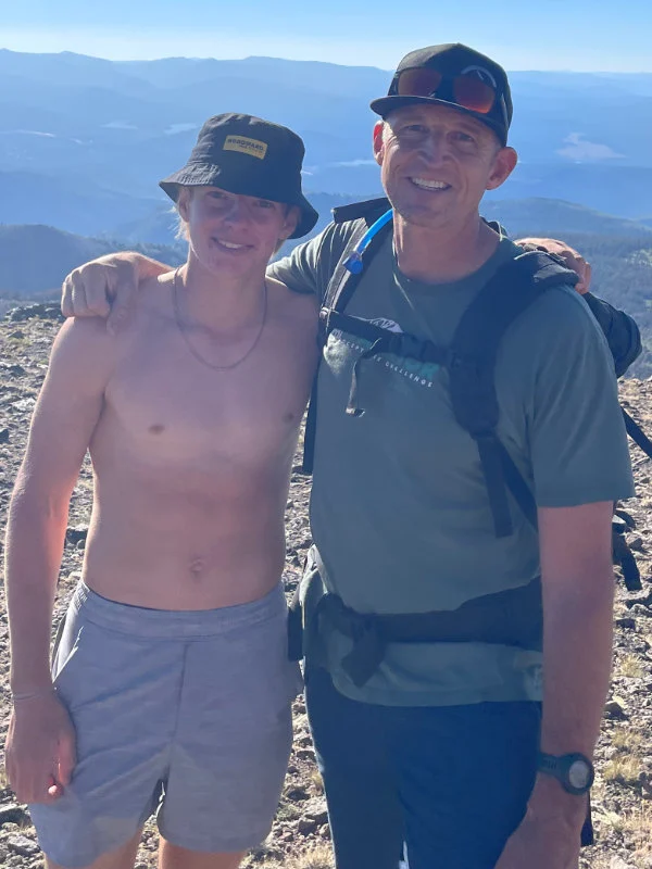 A man and his son pose at the summit of Mount Rose during the Be Warrior Challenge Hike in 2023