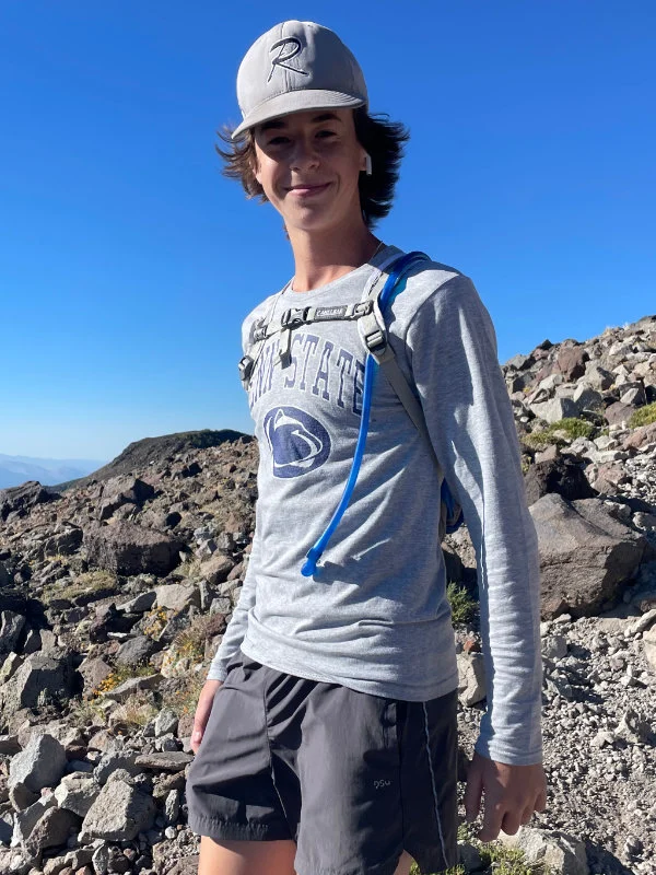 A young man stands at the top of of the Mount Rose Summit during the 2023 Be Warrior Challenge Hike